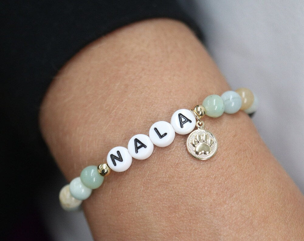 Custom name dog bracelet. It is a gemstone bracelet with plastic letters and a beautiful gold paw print charm.